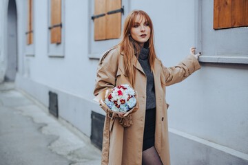 Portrait of seducing red haired woman in retro clothes holding flowers.