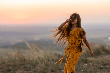 Beautiful little girl of Indian appearance at sunset in summer, long hair,
