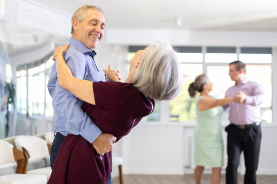Aged couple in their free time engaged in latin dance class and learns movements of cha-cha-cha dance