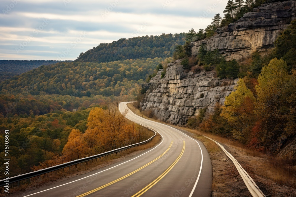 Wall mural  a curve in the road in front of a mountain with trees on both sides and a cliff on the other side.