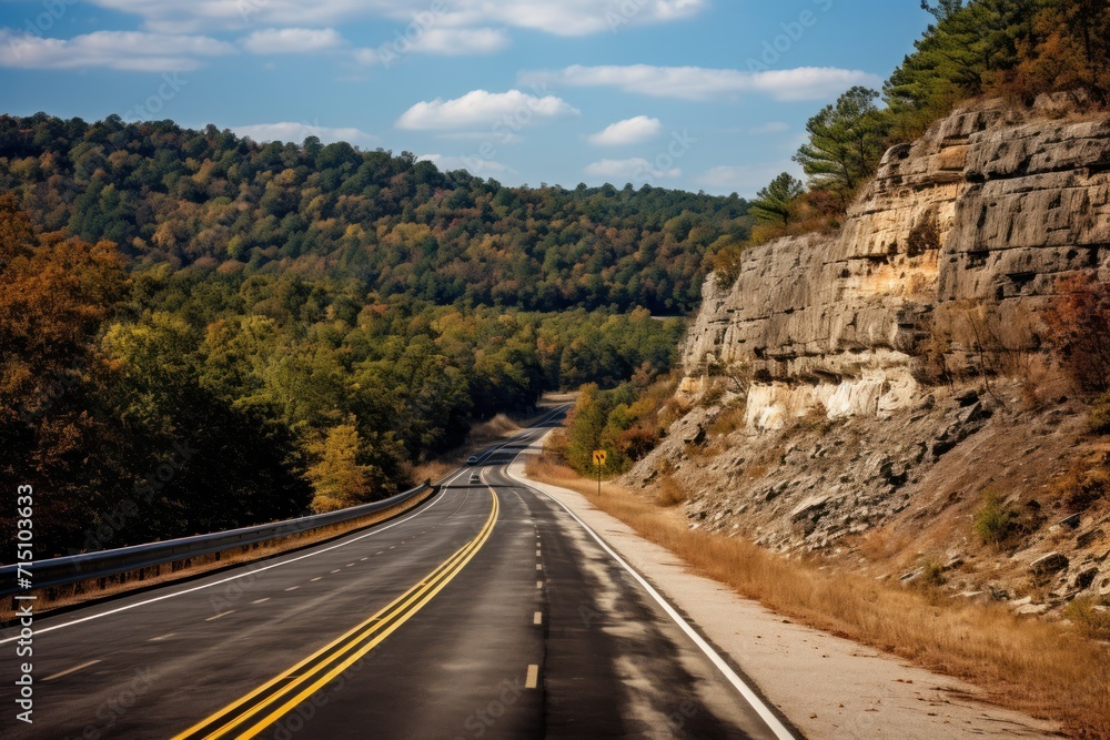 Poster a view of a road in the middle of a mountain with trees on both sides of the road and a cliff on the