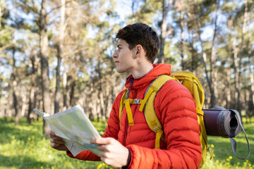 young adult man hiker in the forest with his map