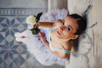 Top view of ballerina in costume holding white rose.