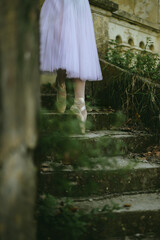Close up of ballerina feet going down rustic stairs en pointe.