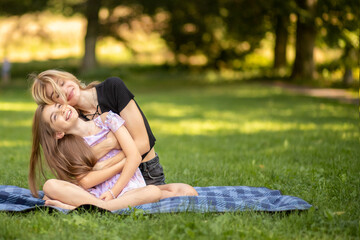Mother and daughter embracing and laughing, lying on a picnic blanket
