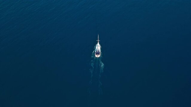 Aerial drone point of view sailboat on tranquil, sunny blue sea. Top down shot