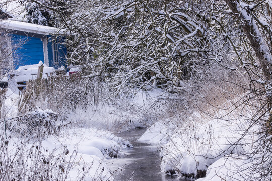 Winterlandschaft mit Bach und blauem Gartenhaus