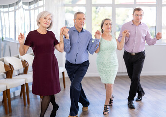 Elderly people with middle-aged man holding hands dancing hava nagila. Dance lessons for amateurs and beginners