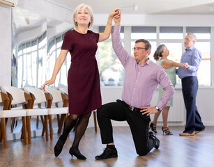 Adult man and elderly woman dance ballroom dance waltz in studio