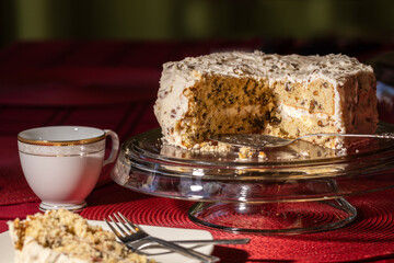 Frosted Buttercream pecan cake on a glass stand on top of red linen covered table