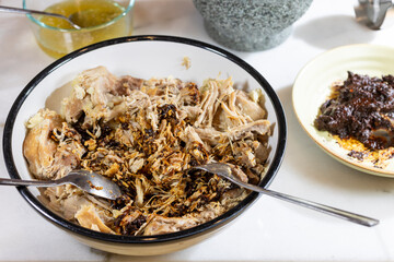 Process of making pulled pork with red ancho chili paste on a marble top kitchen counter