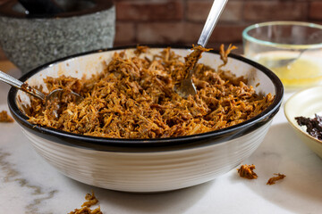 Process of making pulled pork with red ancho chili paste on a marble top kitchen counter