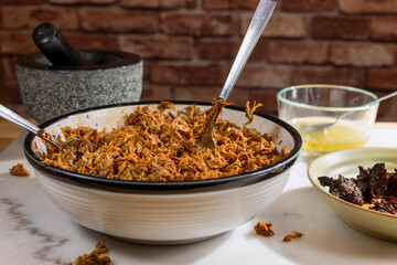 Process of making pulled pork with red ancho chili paste on a marble top kitchen counter