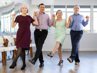 Positive adults forming line while rehearsing traditional Irish stepdance in modern dance studio