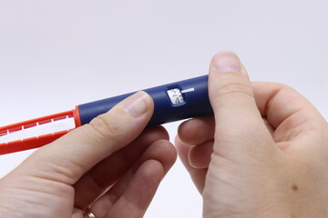 Woman holding a insulin pen and selecting how much UI te patient will receive 