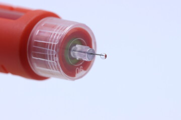 Close up view of a insulin pen with a insulin drop in a white background 