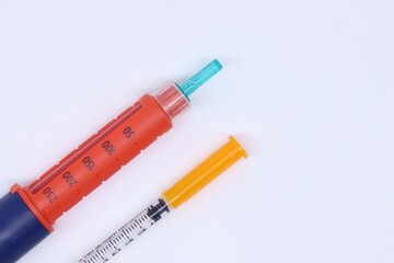 Fototapeta premium Insulin pen and syringe with caps in a white background with copy space in the right side 