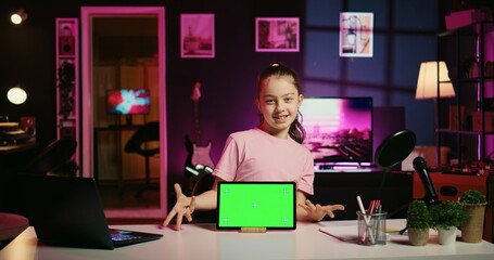 Smiling daughter filming online content with her parent using green screen tablet from sponsoring brand. Happy kid and her mother do internet videos for fans using chroma key device - Powered by Adobe