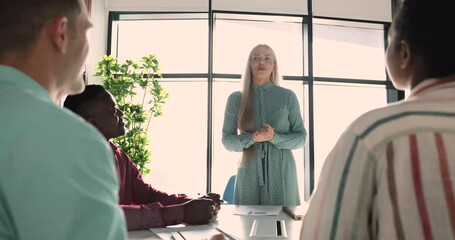 Beautiful businesswoman project leader talking to employees on meeting, standing in front on team, explaining tasks, presenting strategy provide information, make presentation, negotiates with clients