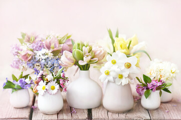 Fototapeta na wymiar Delicate blooming light springtime flowers in vases, spring blossoming floral festive background, bouquets floral card, selective focus, shallow DOF