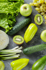 Green Vegetables and Fruits: Avocado, Green Apple, Kiwi, Grapes, Lettuce, Cabbage, Cucumbers, Green Onions and Bell Peppers on Concrete