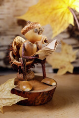 Autumn scene with a little man made of acorns reading a book on the toilet. The picture is suitable...