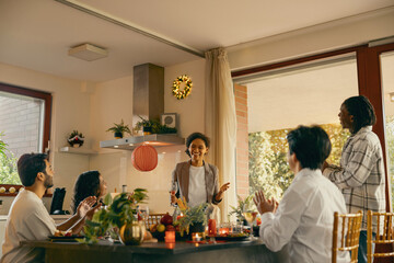 Group of smiling friends enjoying in conversation and drinking wine during Christmas party at home