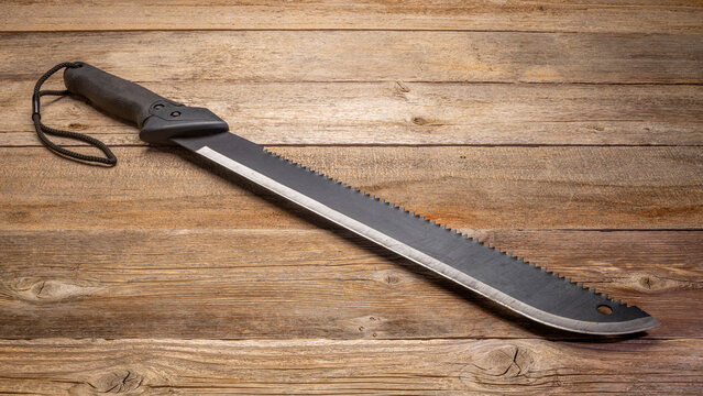 bush clearing machete with carbon steel blade and saw against rustic wooden deck
