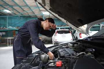 Auto mechanic working in garage. Repair service. Worker mechanics in uniform are working in auto service with lifted vehicle. Car repair maintenance.