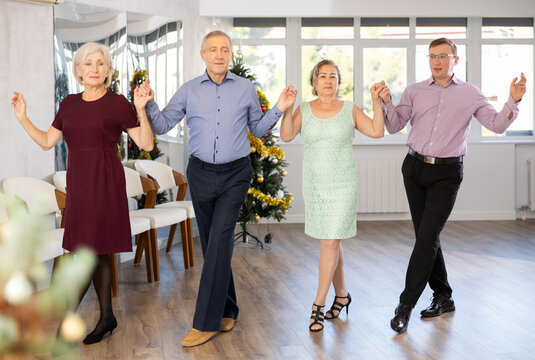 Group of men and women dancing traditional folk dance in studio..