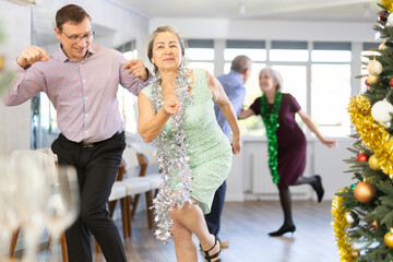 Adult man and elderly woman dance energetic twist dance in studio..
