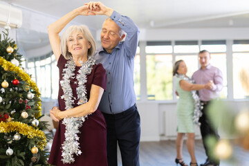 Happy adult man and woman performing ballroom dance in modern dancing room during celebration...