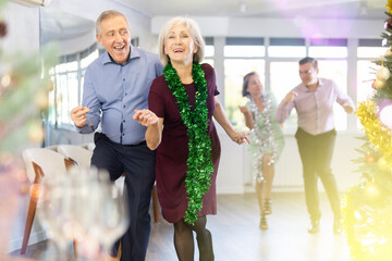 In studio decorated for New Year, elderly man and woman perky dance pair discofox. Energy activity...