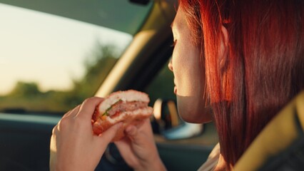 girl opens her mouth eating delicious hamburger, driving car, girl riding front seat car, vacation...