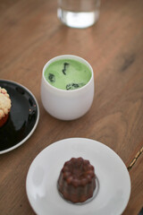 Green tea matcha latte with bakery on wooden table at cafe. Japanese traditional ceramic bowl. Assorted sweet bakery and pastry-
