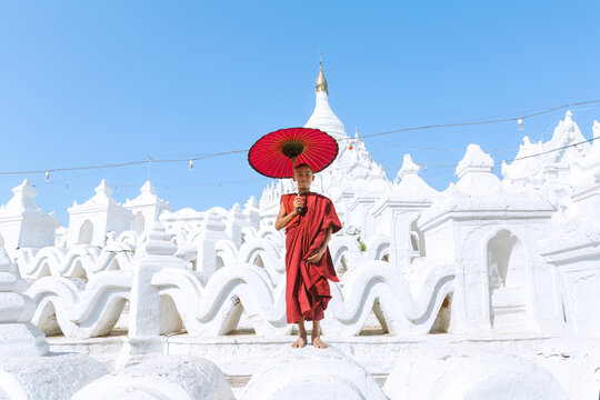 Novice buddhist monk with umbrella on white temple, Myanmar