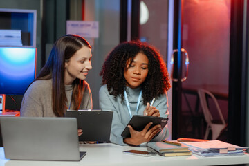 Businesswoman leading team meeting and using tablet and laptop computer with financial. overtime.
