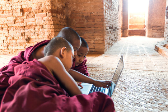 Three novice buddhist monks using laptop computer, Myanmar