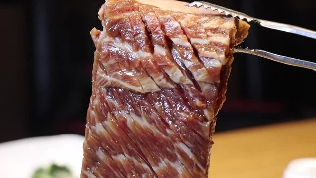 양념이 잘 스며든 칼집난 대왕갈비를 숯불에 노릇노릇 맛있게 구워 가위로 자르는 모습