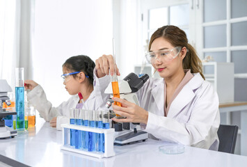 portrait young asian woman as a mentor teaching student in chemical laboratory,scientist in uniform working in workplace room