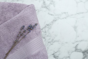 Violet terry towel and dry flowers on white marble table, top view. Space for text