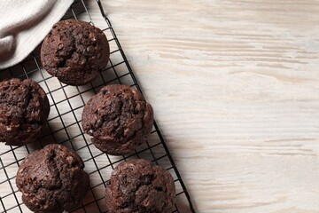 Delicious chocolate muffins on light wooden table, top view. Space for text