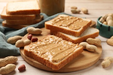 Fototapeta na wymiar Delicious toasts with peanut butter and nuts on light wooden table, closeup
