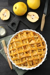 Tasty homemade quince pie and fresh fruits on black wooden table, flat lay