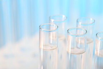 Laboratory analysis. Many glass test tubes on light blue background, closeup and space for text