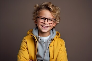Portrait of a smiling little boy in a yellow jacket and glasses