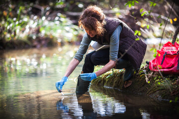 Mid Adult Biologist Collecting Samples of Water for Further Examination from a Water Stream in...