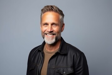Portrait of a happy mature man in leather jacket over grey background