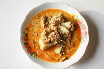 Lontong sayur or vegetable rice cake is a typical Indonesian food on a white plate with an isolated white background
