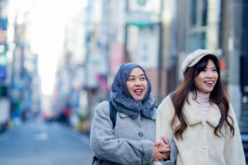 woman girl tourist Two Asian friends but different religions, one of whom is a Muslim girl. Walking tour of the city, city view, traveling in Japan Tokyo. with fun She is traveling in the city area.